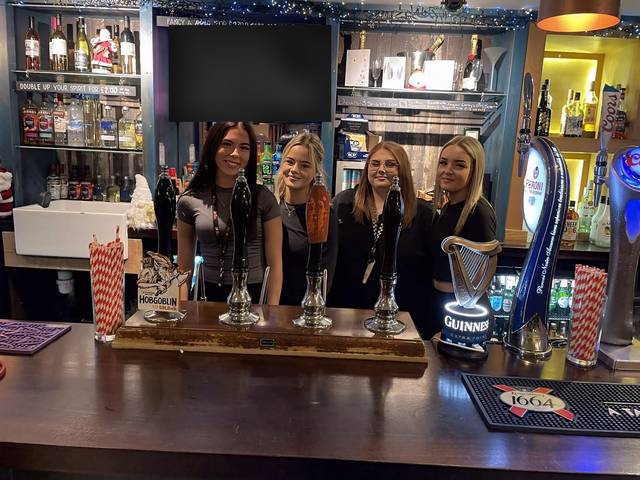 Four Teal Farm bar staff smiling behind the bar, by the hand pumps
