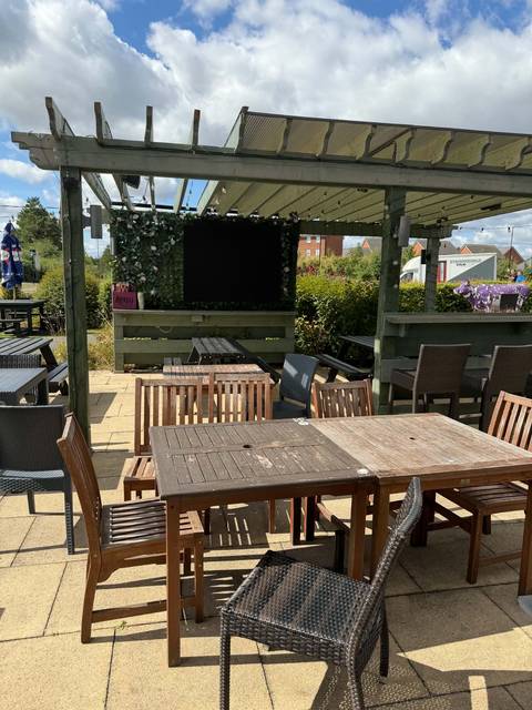 The covered pergola in the Teal Farm beer garden on a sunny day, with its outdoor TV