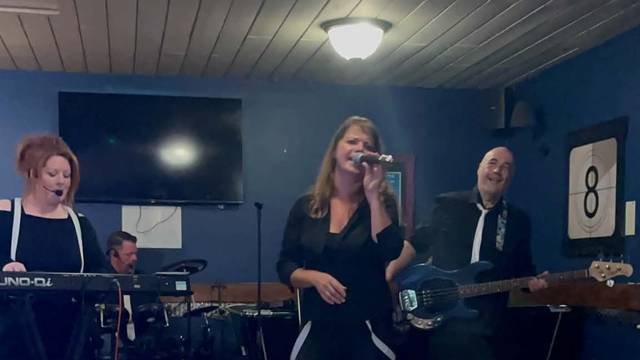 A live band at Teal Farm, the singer at the mic in front of a switched-off TV