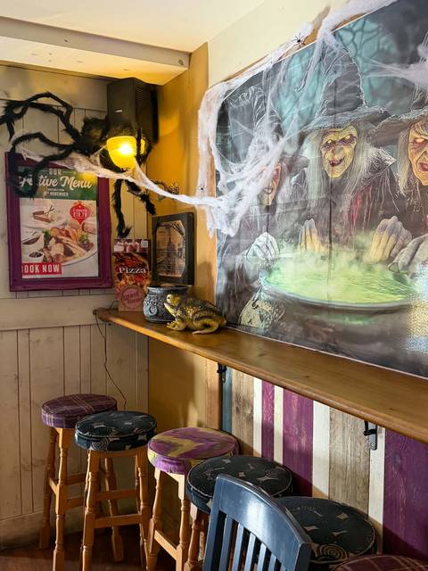 A Halloween corner at Teal Farm with a witch and cauldron mural, cobwebs and bar stools